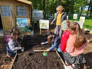 Atelier jardinage pour les enfants au jardin-école de Montlouis-sur-Loire (37) Enfants qui jardinent accompagnés de Maryline, bénévole chez Jardinot